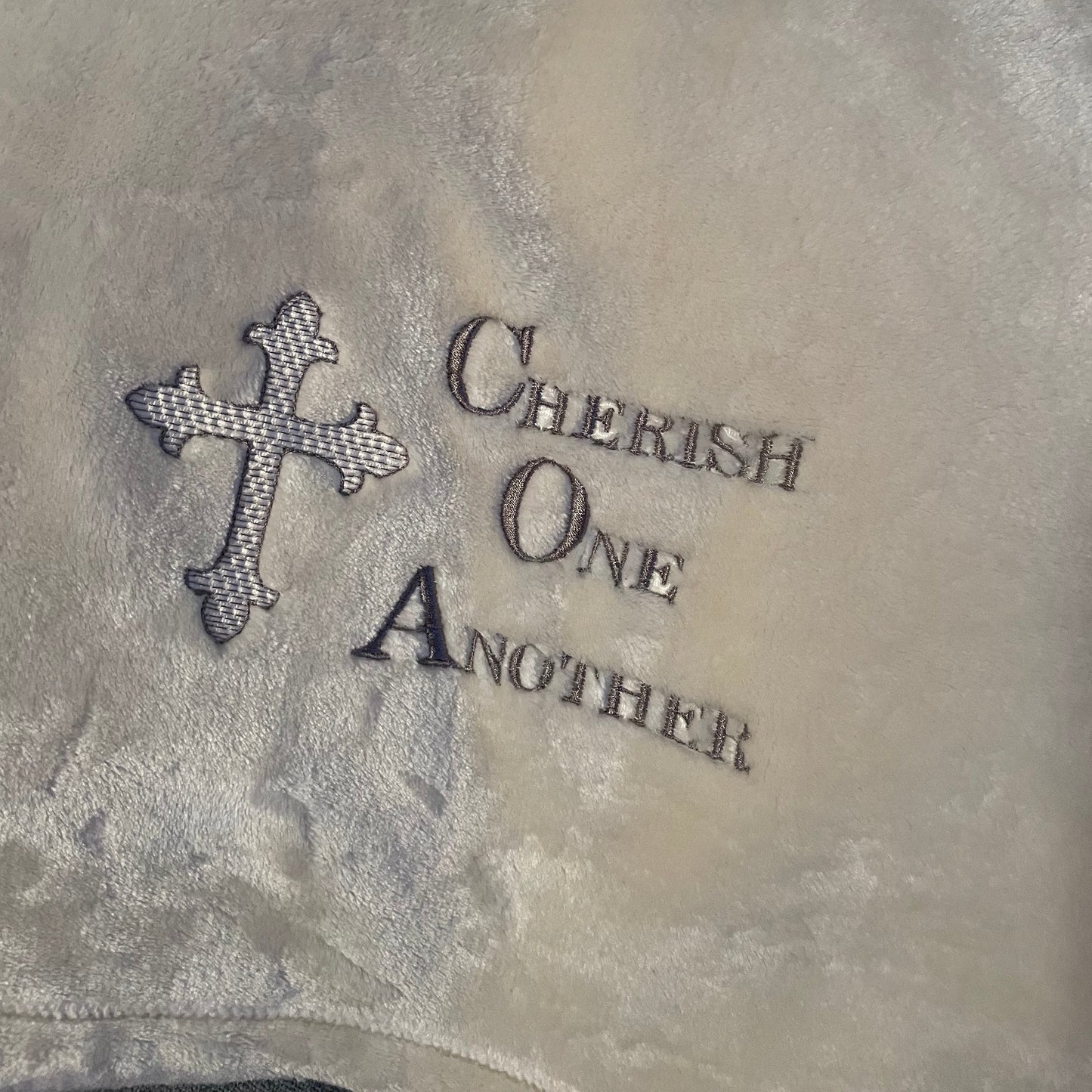 Cream throw embroidered with the text: "Cherish One Another"
