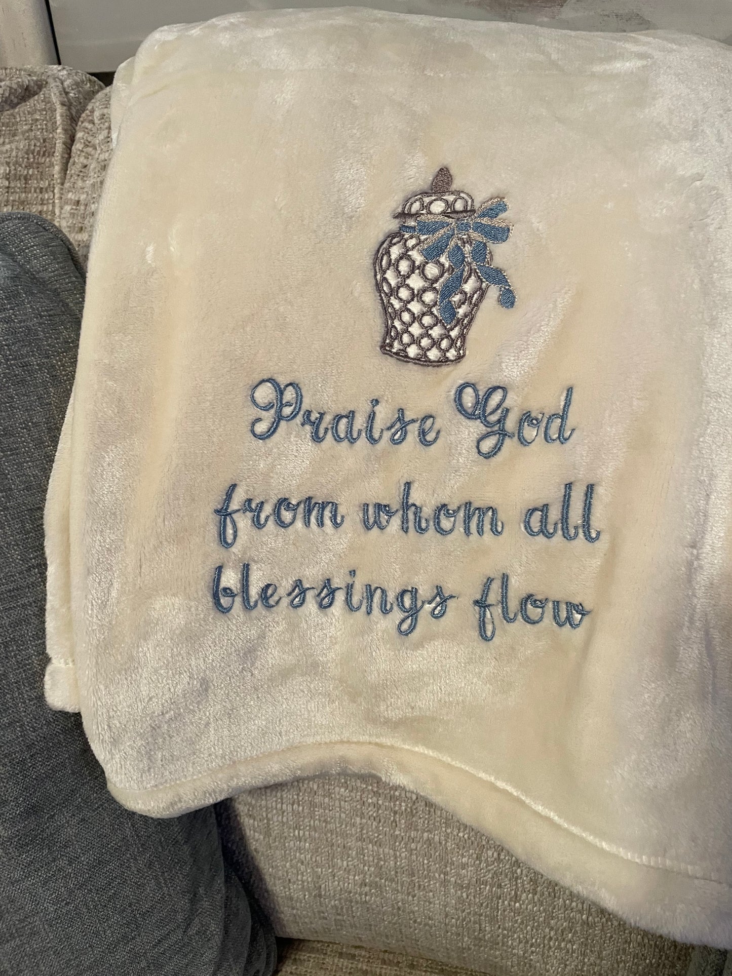 Cream throw embroidered with the text: "Praise God From Whom All Blessings Flow"