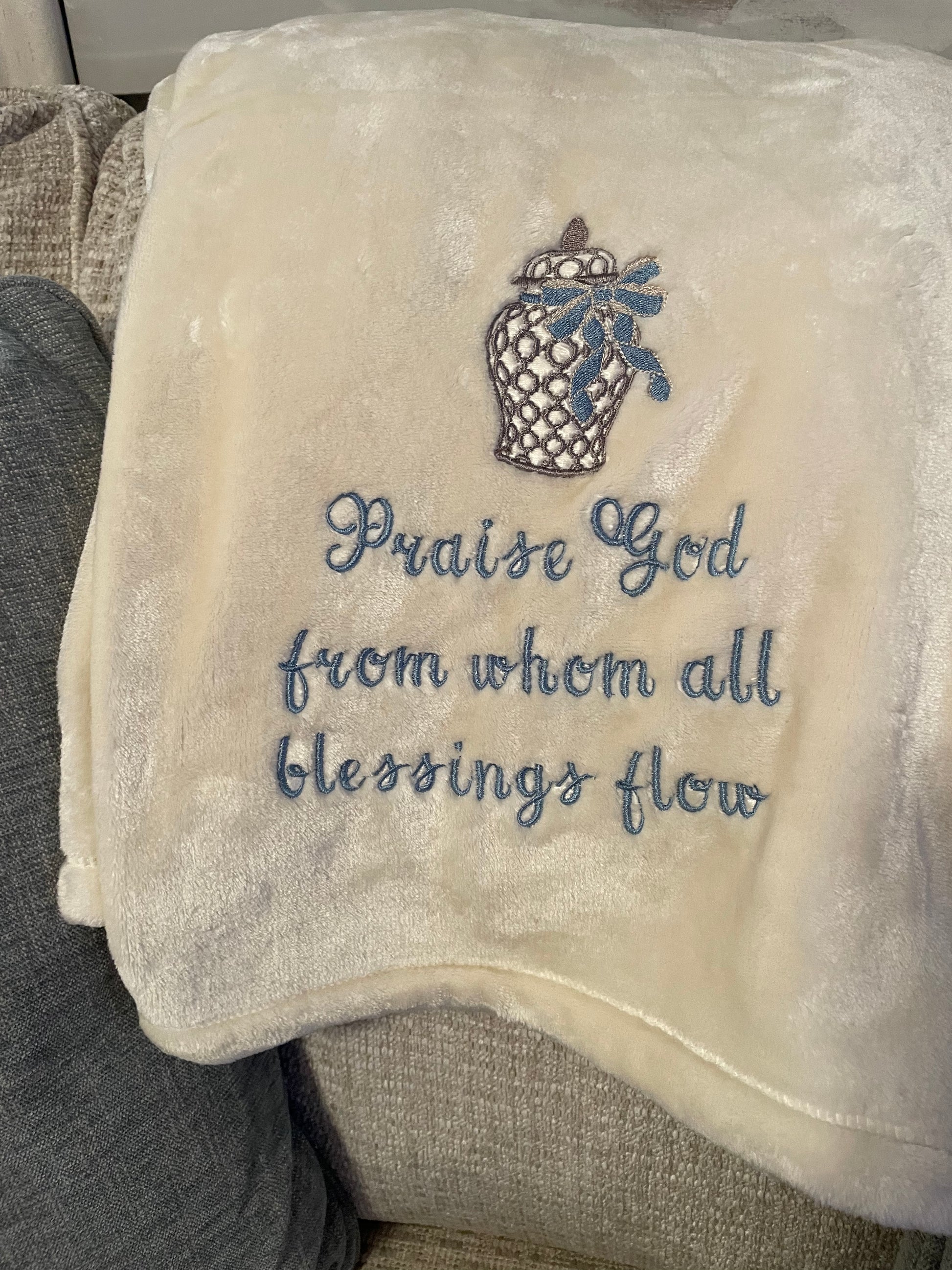 Cream throw embroidered with the text: "Praise God From Whom All Blessings Flow"